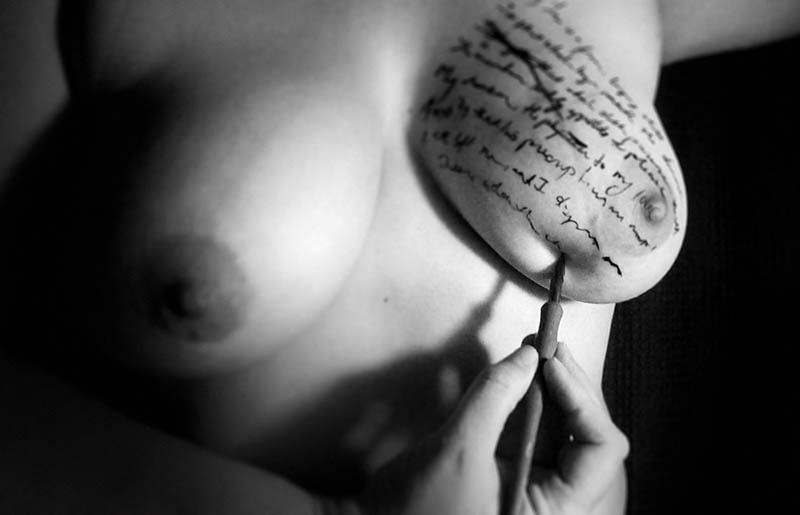 Woman writing on her breast in pen and ink.