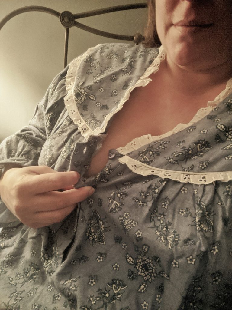 woman unbuttoning an old fashioned blue flannel nightgown