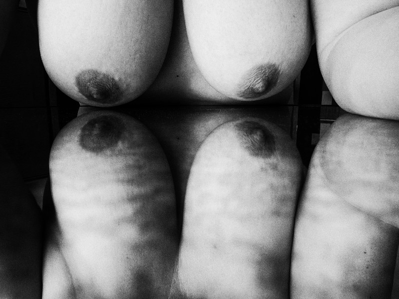 Reflection of nude breasts in black and white