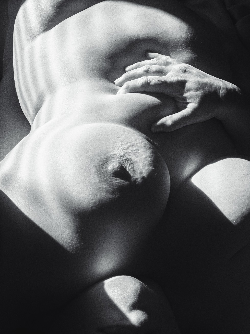 black and white photo, nude woman, sharp contrast, hand grabbing belly