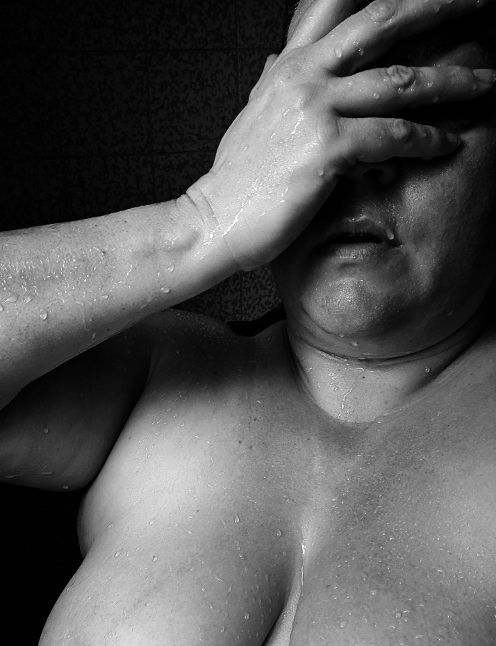 Black and white photo, woman in shower, hand over face
