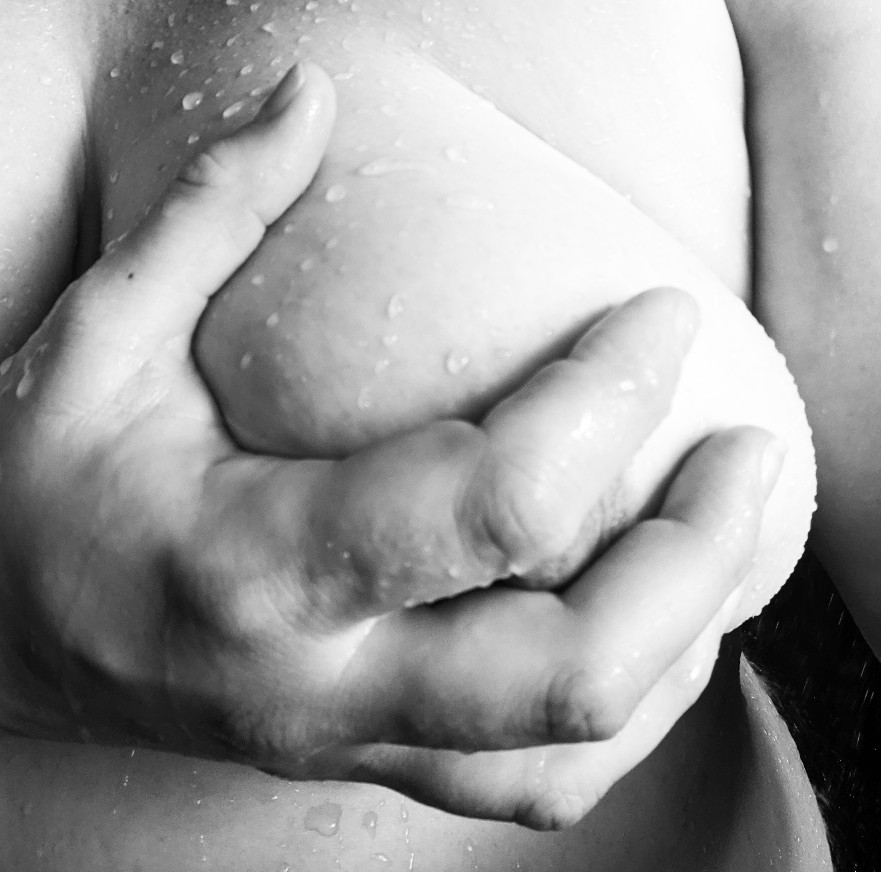 Black and white hand holding breast in shower